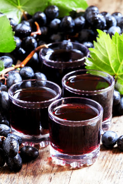 Fresh dark grape juice and fresh berries on old wooden table, se