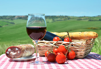 Red wine, bread and tomatos on the chequered cloth against Tusca