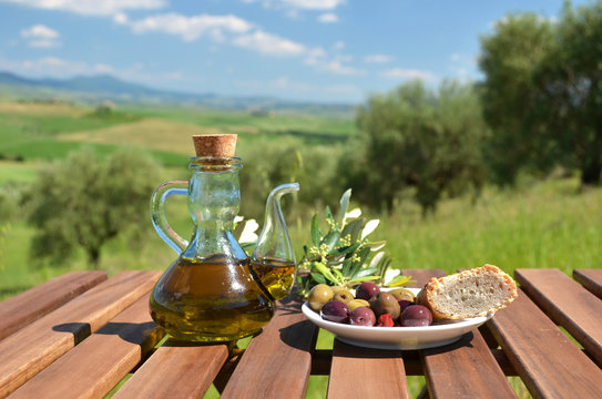 Olive oil, olives and bread on the wooden table against Tuscan l