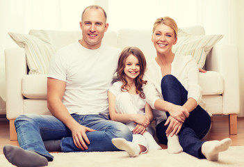 parents and little girl sitting on floor at home