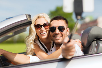 happy couple in car taking selfie with smartphone