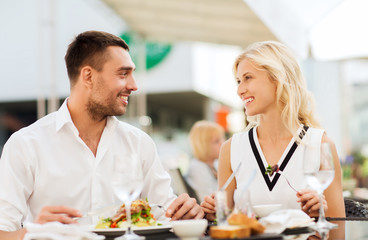 Obraz na płótnie Canvas happy couple eating dinner at restaurant terrace