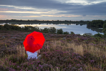 lady with red umbrella on heathland at sunrise
