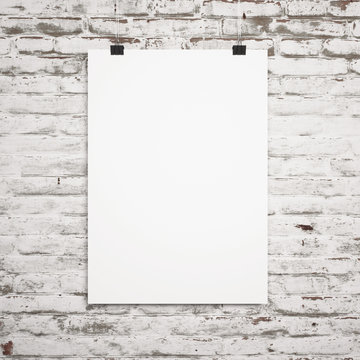blank poster hanging with clips on a background of white brick wall
