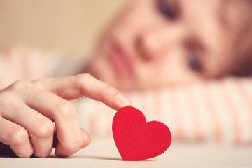 Sad and upset girl is touching heart symbol with finger