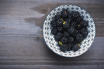 bowl with wild backberries on a wooden table