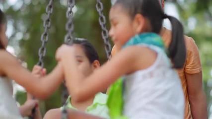 Father pushing his daughters on a tire swing in a park