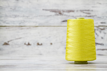 Spool of Synthetic Green Thread on White Wooden Background