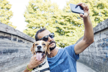 young man takes a selfie with his dog - obrazy, fototapety, plakaty