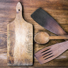 cutting board, spoon and spatula on wooden background
