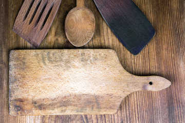 cutting board, spoon and spatula on wooden background

