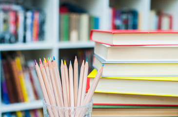 Colored pencils with pile of books in background