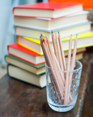 Colored pencils with pile of books in background