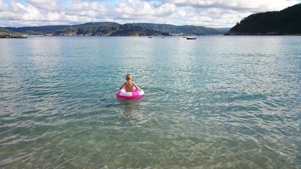 Niño con flotador solo ante el mar
