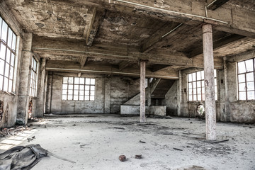 Fototapeta na wymiar Empty industrial loft in an architectural background with bare cement walls, floors and pillars supporting a mezzanine