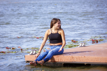Adolescente de 15 años en el embarcadero. Chica rubia adolescente pasando una tarde de verano junto al rio.