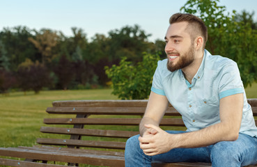 Naklejka na ściany i meble Young man relaxing on park bench 