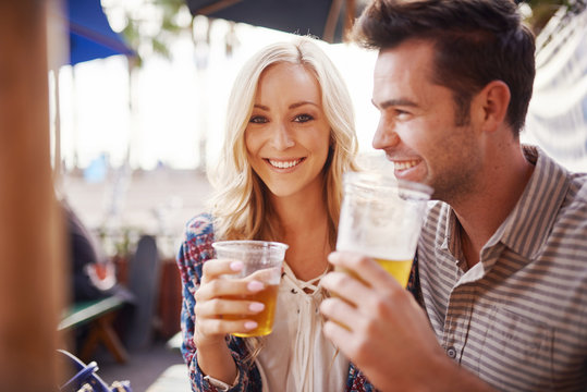 Romantic Couple Drinking Beer Together In Outdoor Beach Side Pub Or Bar