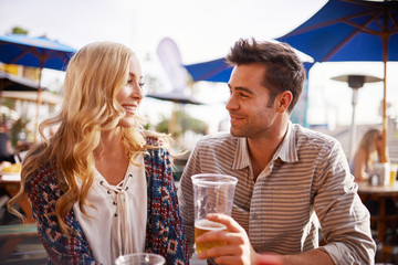 couple drinking beer in beach side outdoor pub or bar together