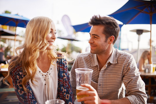 couple drinking beer in beach side outdoor pub or bar together