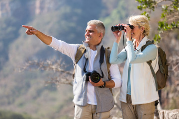 female hiker using binoculars while husband pointing