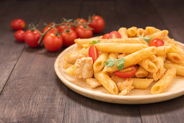 Penne pasta in tomato sauce with chicken on a wooden table.
