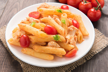 Penne pasta in tomato sauce with chicken on a wooden table