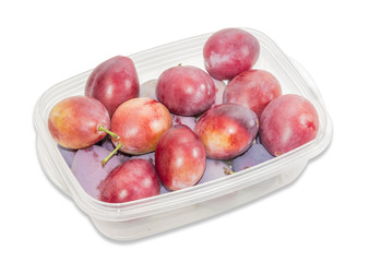 Plums in plastic tray on a light background