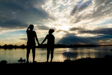 Silhouette of couple beside the river with beautiful sunset