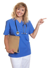 Krankenschwester mit blonden Locken zeigt zu Seite