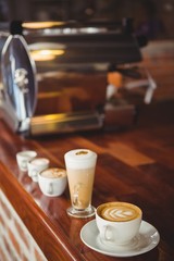 Several hot beverages in a row on the counter