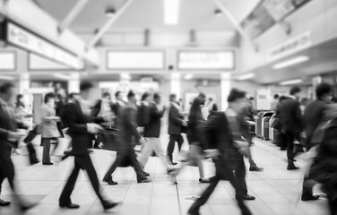 business people walking in the subway station. motion blurred black and white filter - Powered by Adobe