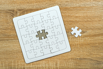 Piece missing from jigsaw puzzle on wooden table