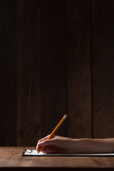  woman's hand writing on paper over wooden table