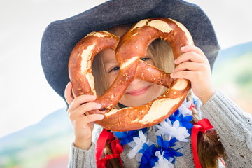 Cute girl with bavarian hat and big pretzel.