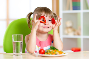 kid girl having fun with food vegetables in children room