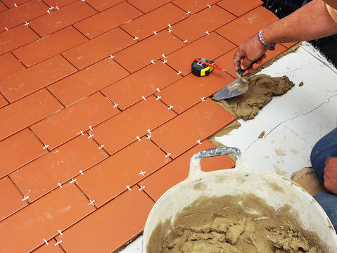 Bricklayer laying floor tiles in the courtyard of a house