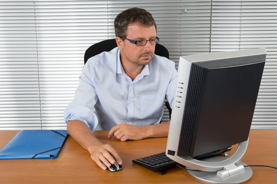 Close-up portrait of a balack and grey haired man with computer at desk