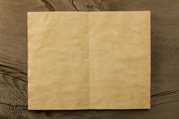 open old vintage book on the aged wooden background. Two clean sheet of paper.