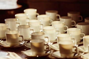 Closeup image of row of empty white tea cups with spoons