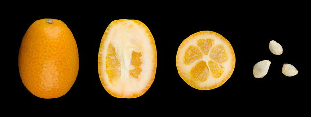 Oval kumquats with seeds in a row closeup. A whole kumquat, two cut in half and three seeds. Macro photo from above on black background.