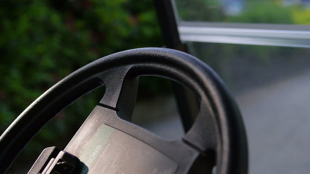 Close up of a black steering wheel in a golf car. Camera drives from left to right and ended blurred. 