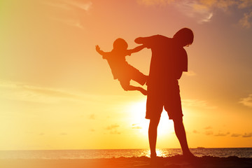 Fototapeta premium silhouettes of father and son having fun at sunset