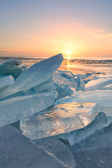 Frozen blocks of ice on the water in winter with a blue sky in the background at sunrise with a golden glow  - 89908972