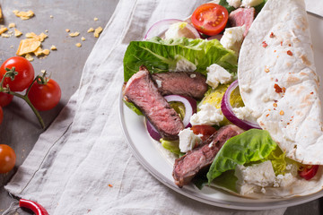 Mexican tortillas with green fresh salad filling, beef, onions, tomatoes with gucamole and tortilla chips on te vintage board