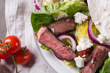 Mexican tortillas with green fresh salad filling, beef, onions, tomatoes with gucamole and tortilla chips on te vintage board