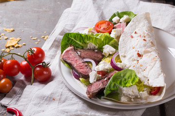 Mexican tortillas with green fresh salad filling, beef, onions, tomatoes with gucamole and tortilla chips on te vintage board