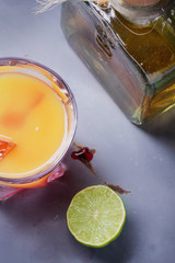 Tequila Sunrise served in a highball glass with ice, grenadine and lime