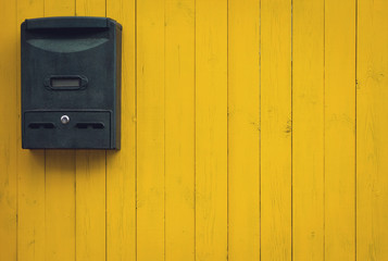 Old mailbox on a yellow wooden background