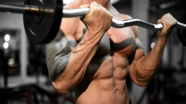 Muscular bodybuilder guy doing exercises in gym